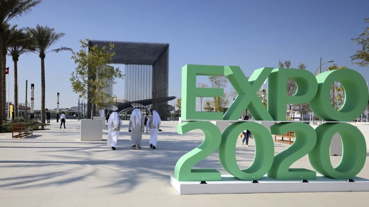 The logo of Dubai Expo 2020 and people from all over the world visiting the exhibition 