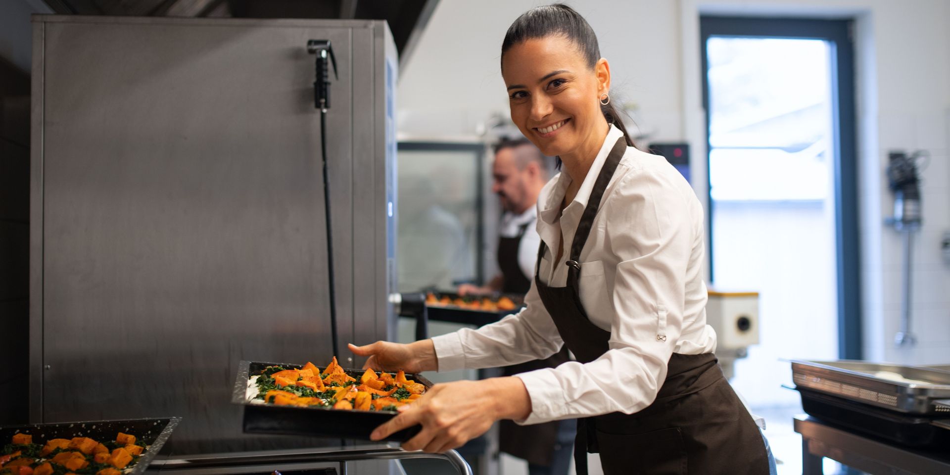 An employee working at a restaurant and holding a food tray