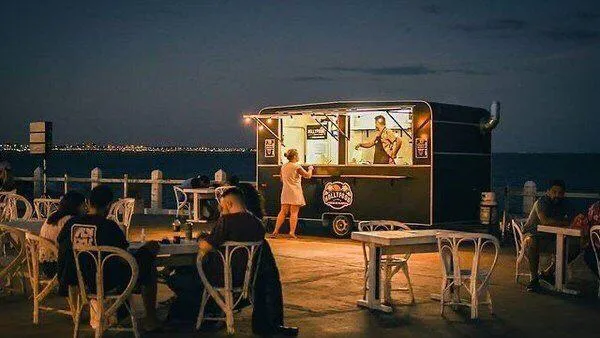 A food truck operating seasonally at night and serving customers food 