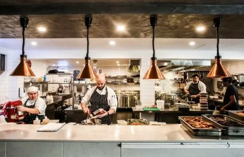 Employees and chefs working and preparing food at the restaurant’s kitchen
