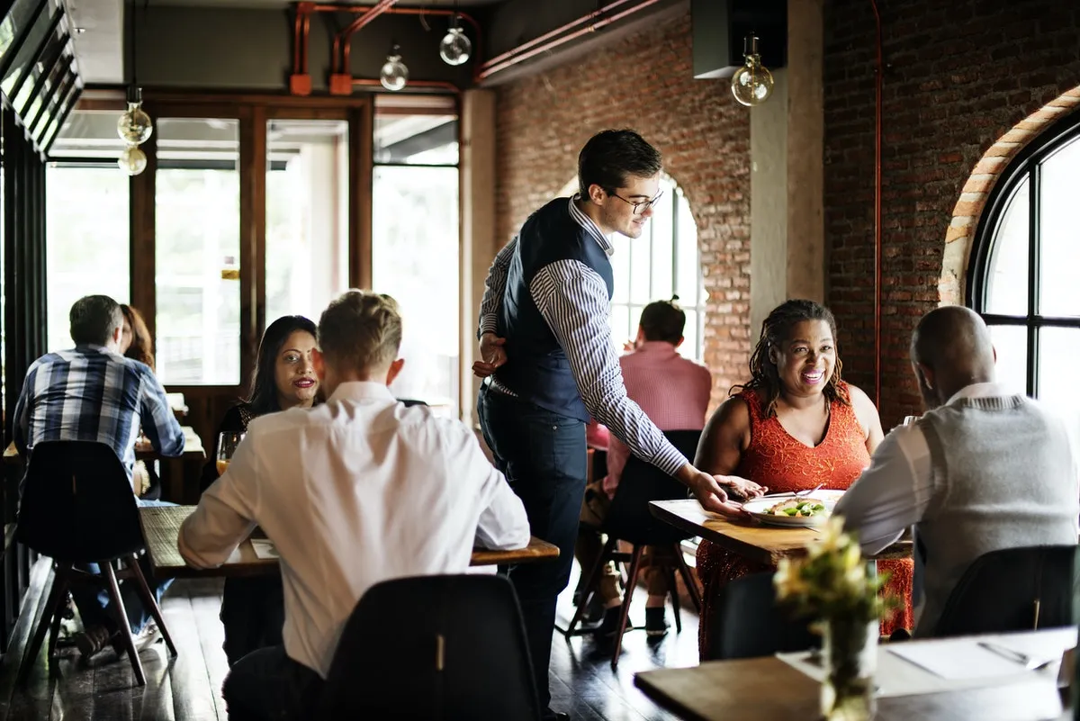 A restaurant full of customers and a waiter serving his section