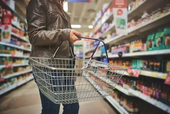 A customer holding a basket and shopping in the supermarket