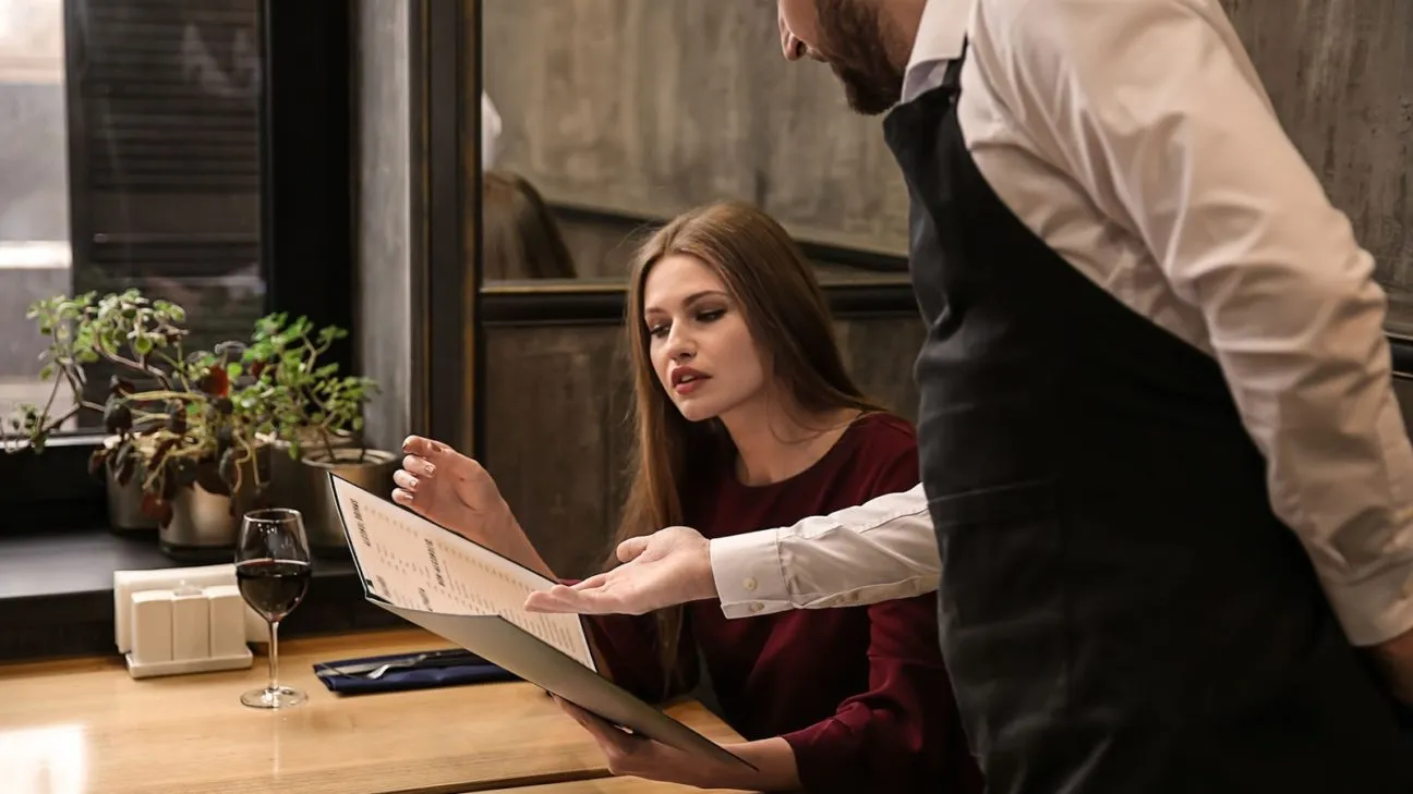 menu pricing strategies: a waiter helping a customer with the menu