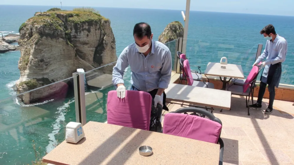 A waiter cleaning a table at a restaurant wearing a mask during the pandemic