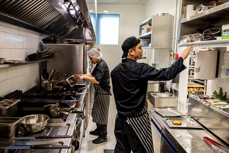 الموظفون والطهاة يعملون ويجهزون الطعام والطلبات في مطبخ المطعم