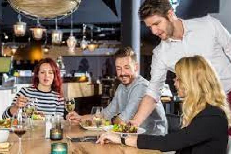 زيادة مشاركة العملاء في المطاعم: نادل يقدم الطعام للزبائن ويتفاعل معهم