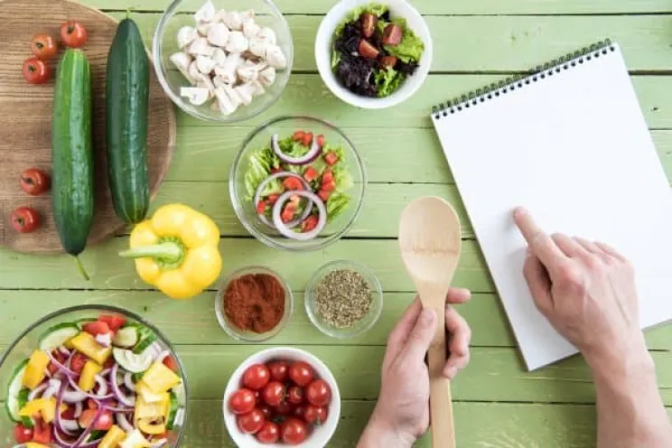 A picture of a chef writing the instructions of his recipes with the ingredients 
