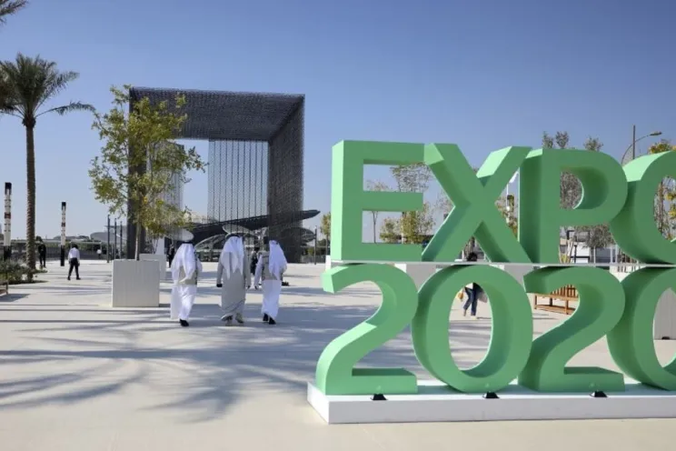The logo of Dubai Expo 2020 and people from all over the world visiting the exhibition 