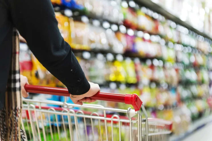 A customer pushing a shopping cart in a supermarket 