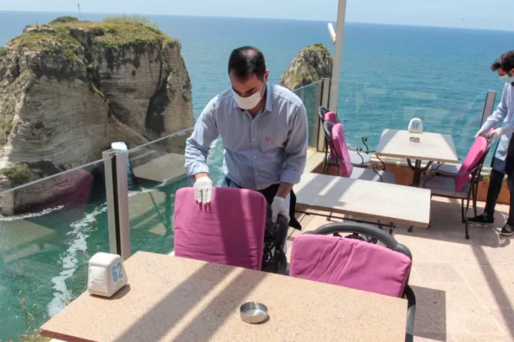 A waiter cleaning a table at a restaurant wearing a mask during the pandemic